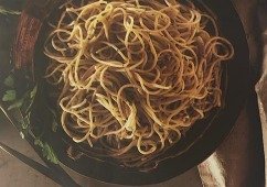 Assiette de spaghettis à l'ail et aux anchois fondants parsemée de persil frais et parmesan.