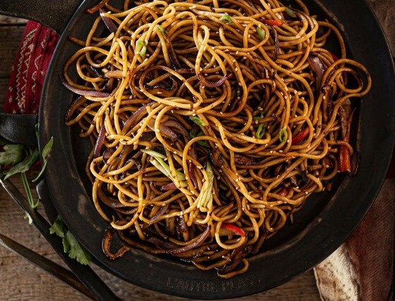 Assiette de spaghettis à l'ail et aux anchois fondants parsemée de persil frais et parmesan.